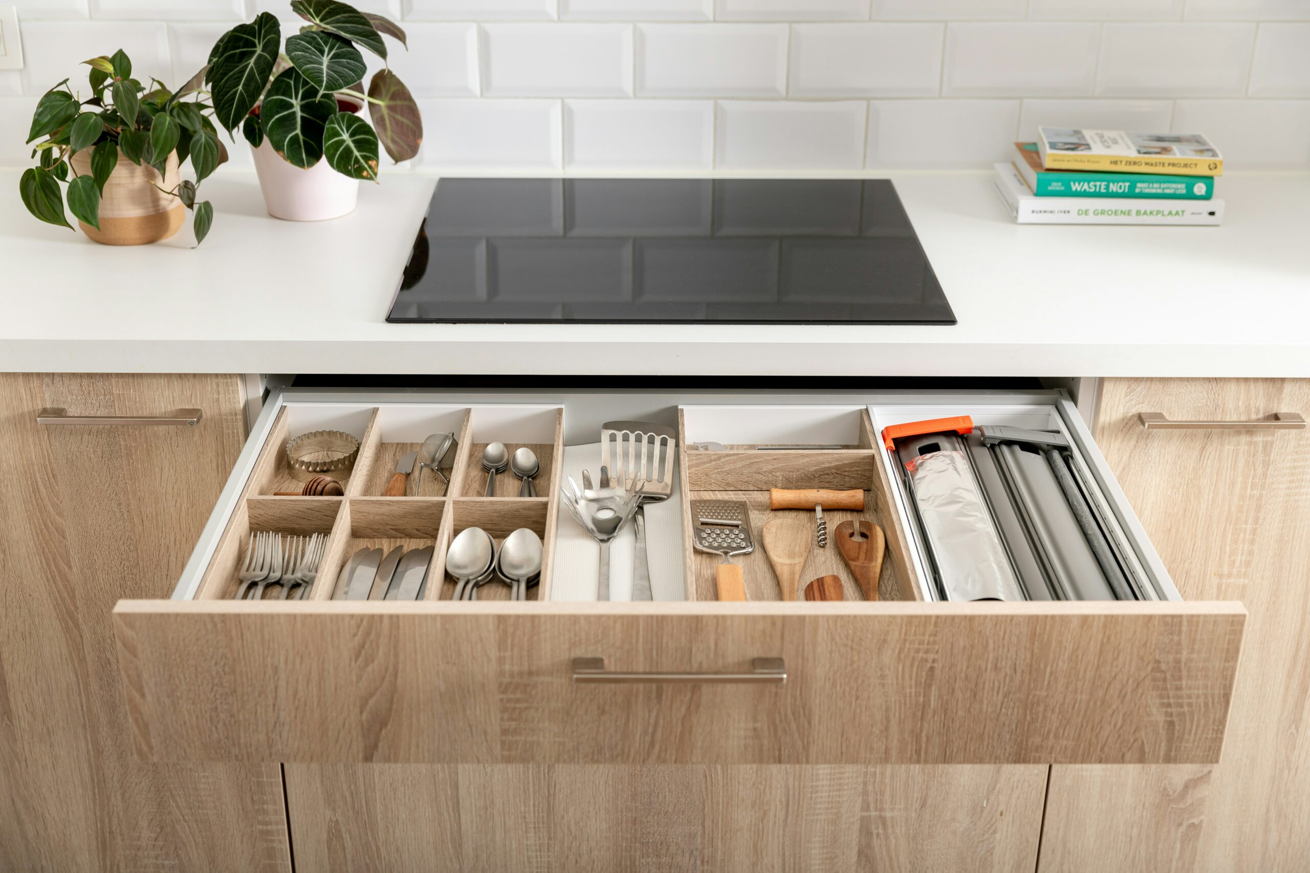 Cajón de cocina ordenado con utensilios y una planta pequeña